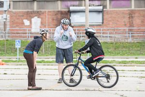 BikeWalkKC Education Outreach Coordinator, Laura, and East teacher, Mr. Patrick Brier, coaching a student on hazard maneuvers. 