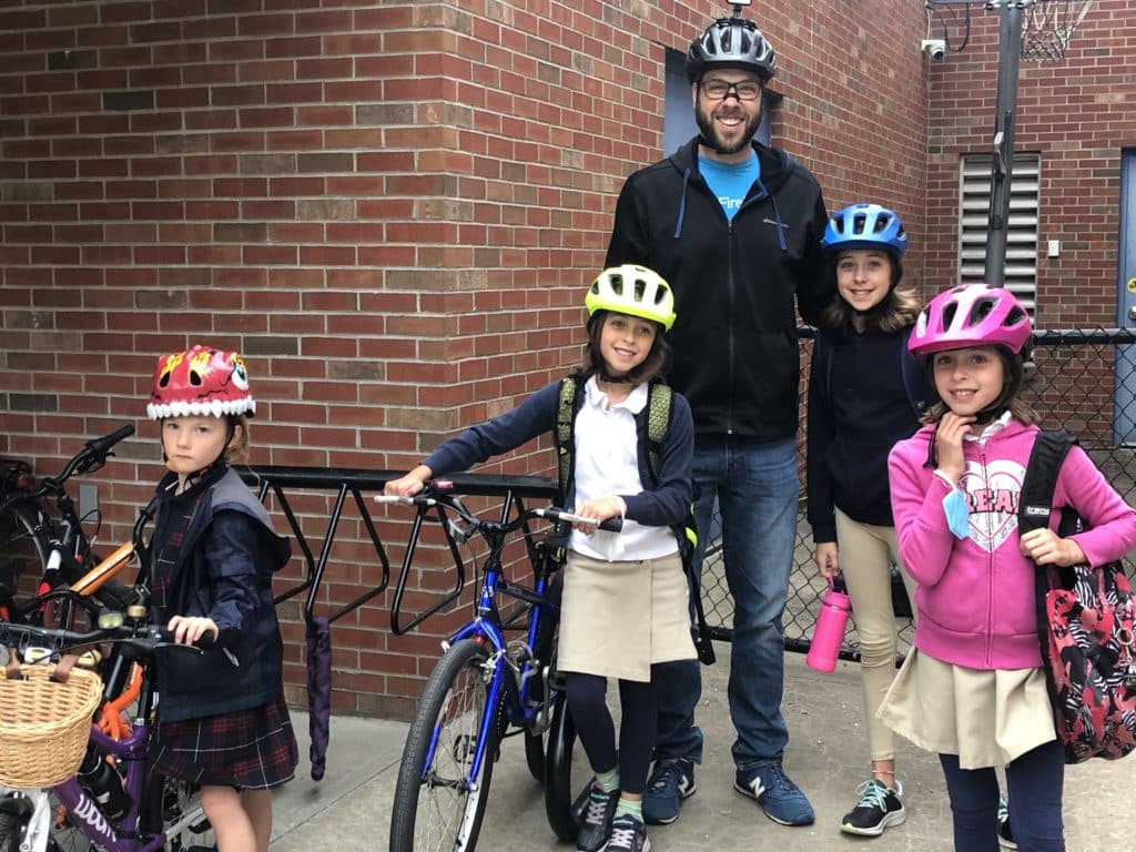 An adult and four children pose with their bikes and helmets at Academie Lafayette's new bike rack