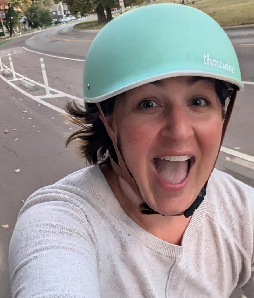 Ellen cheers with joy while riding her bike in a protected bike lane.