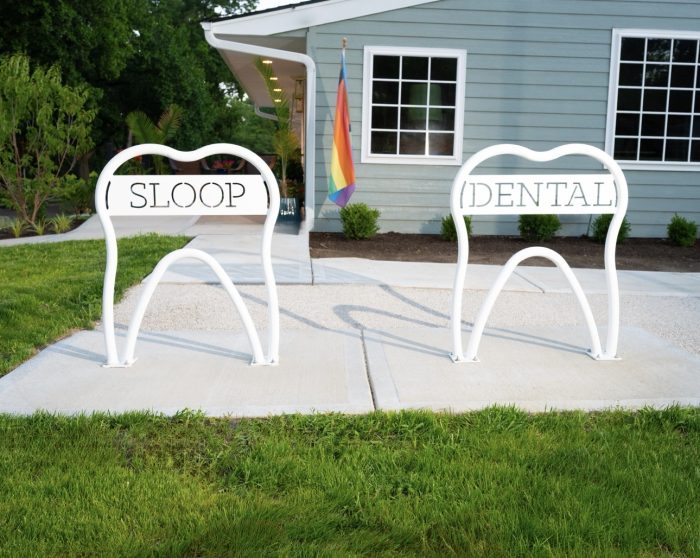 Bright white tooth-shaped and branded bike racks at Sloop Dental Co. in Brookside