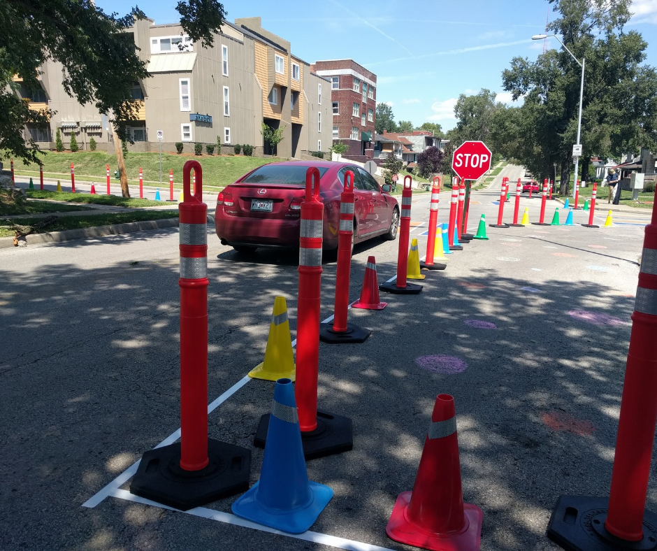 A driver stops at a temporary stop sign. The intersection has been narrowed using cones and tape.